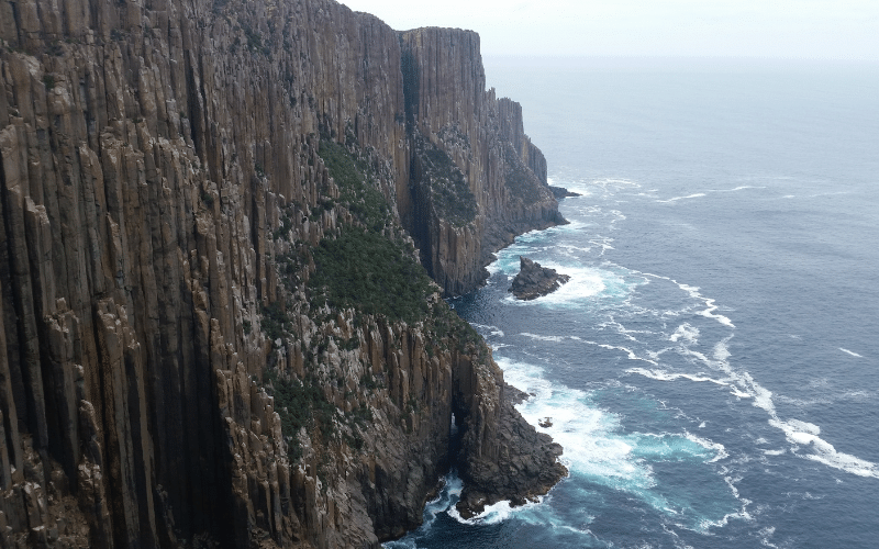 Columnas de basalto cubiertas de vegetación que forman acantilados junto al mar en Tasmania, Cabo Raoul
